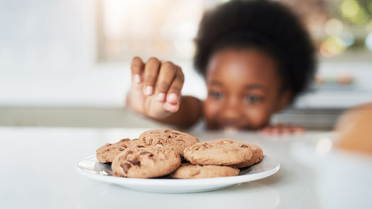 little girl stealing cookies at home