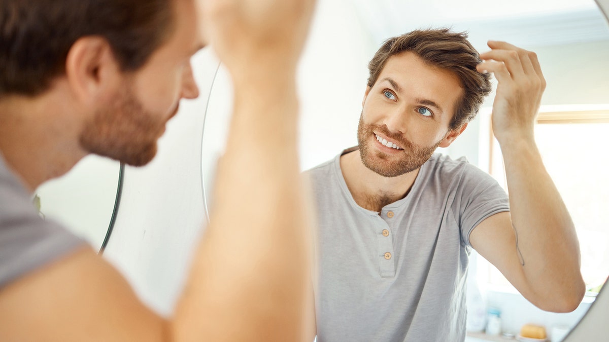 man combing his hair in a bathroom at home