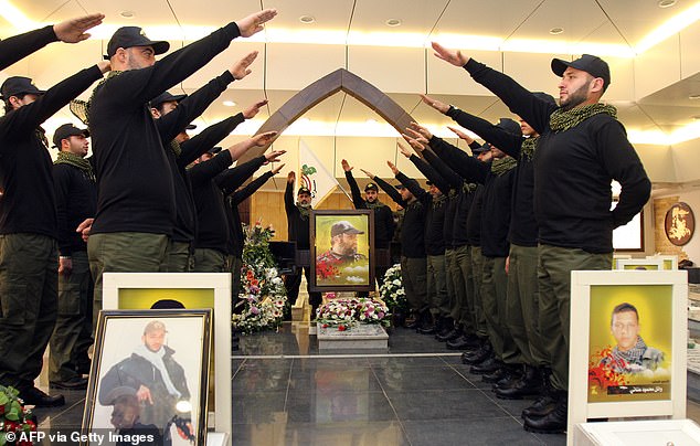 Lebanese Hezbollah militants gesture as they visit the grave of Hezbollah commander Imad Mughnieh (C-portrait), who was killed in a car bombing in the Syrian capital Damascus in 2008