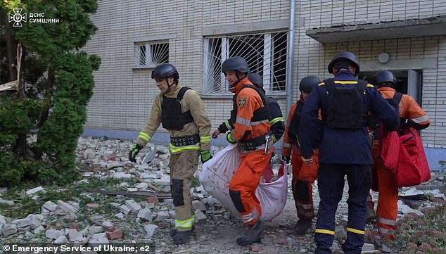 Emergency response teams carry a person out of the building in a blanket