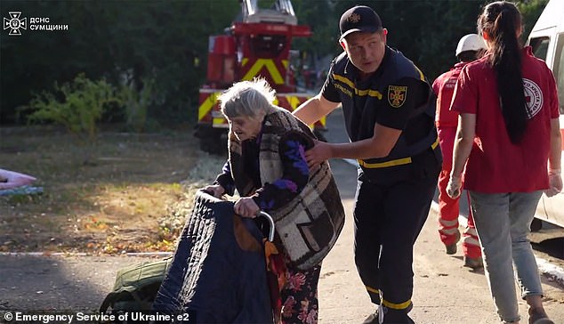 An elderly woman is helped out of the retirement home to safety by a rescuer