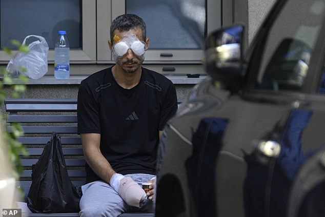 A man who was injured by one of the handheld exploding devices in recent days sits outside a hospital as he waits for treatment in Beirut