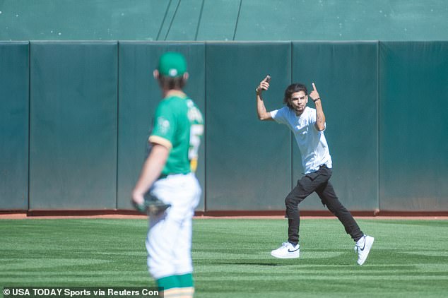 A fan runs onto the field during the ninth inning of the final Athletics game in Oakland