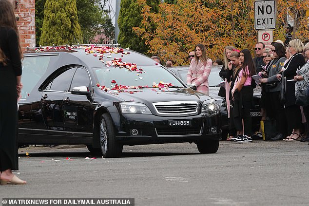 Mourners covered the hearse in petals before it left for the cemetery after the funeral service