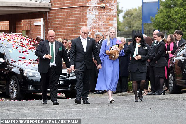 Charlotte O'Brien's parents are pictured, centre, in front of the hearse after the funeral on Friday