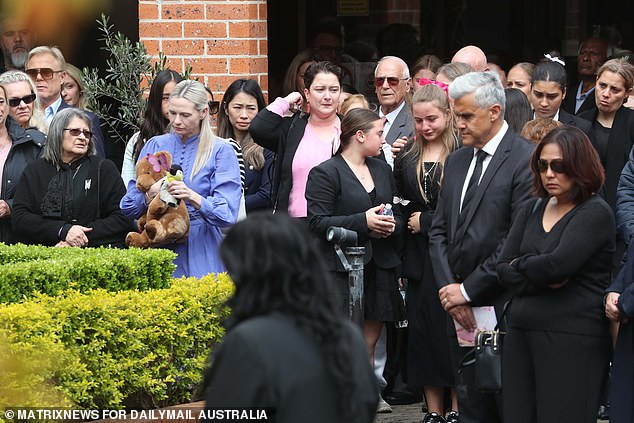 Mourners gathered around the hearse after the service on Friday (pictured)