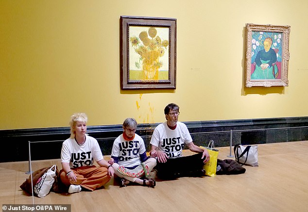 The Just Stop Oil activists sit on the floor in front of one of the Sunflowers painting that was covered in soup