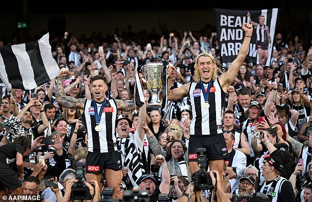 Magpies players Jamie Elliott (left) and Darcy Moore celebrate with their premiership medals after winning the 2023 grand final