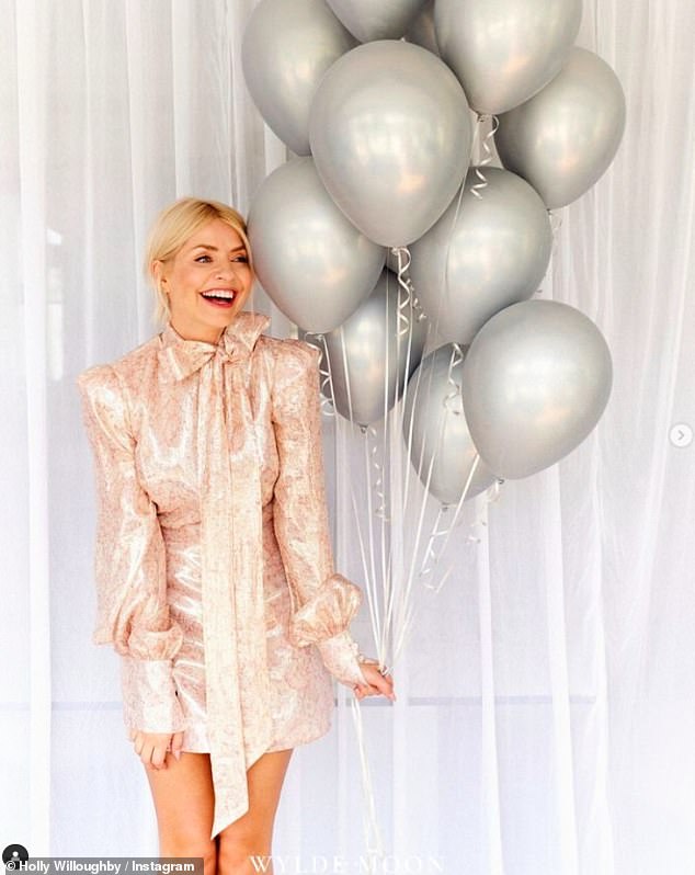 She looked stunning in a light pink leggy dress with cute bow detailing on it as she posed with some silver balloons