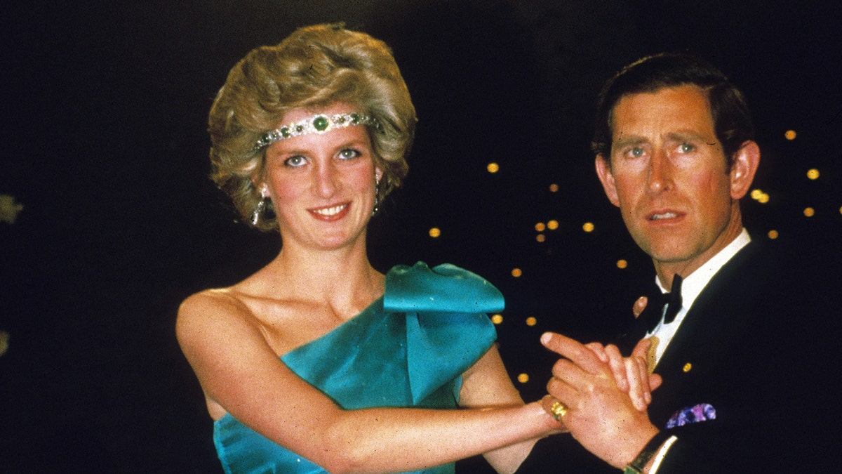 Princess Diana in a jeweled headband and an off-shoulder emerald dress dancing with Prince Charles.