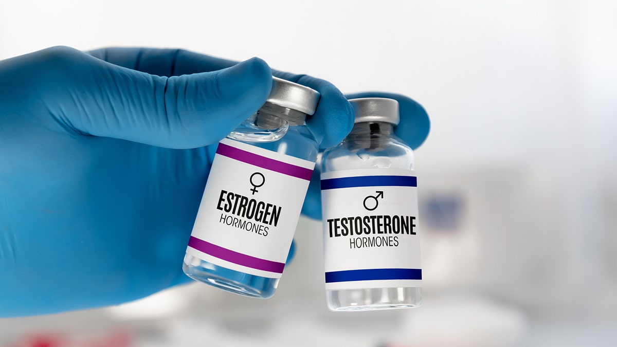 Hand of doctor with two injection vials for treatment with Testosterone and Estrogen hormones