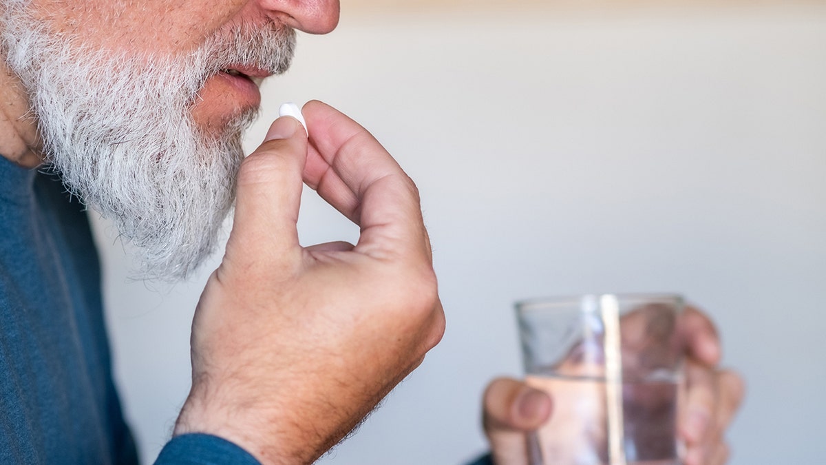 man puts pill in mouth