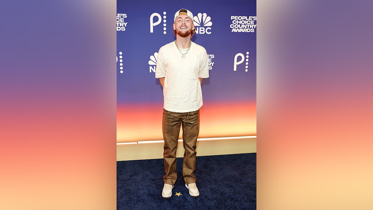 Bailey Zimmerman wearing a white shirt and brown pants on the red carpet at the 2024 People's Choice Country Awards.