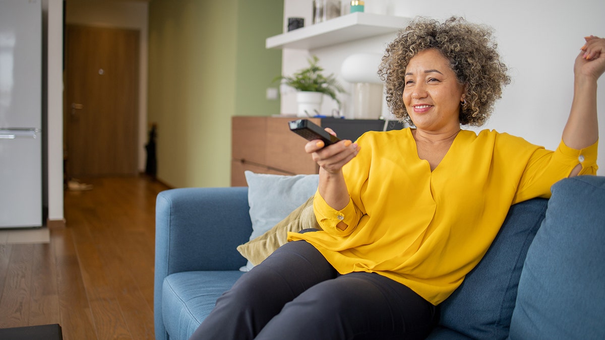 Older woman by herself watching TV on the couch