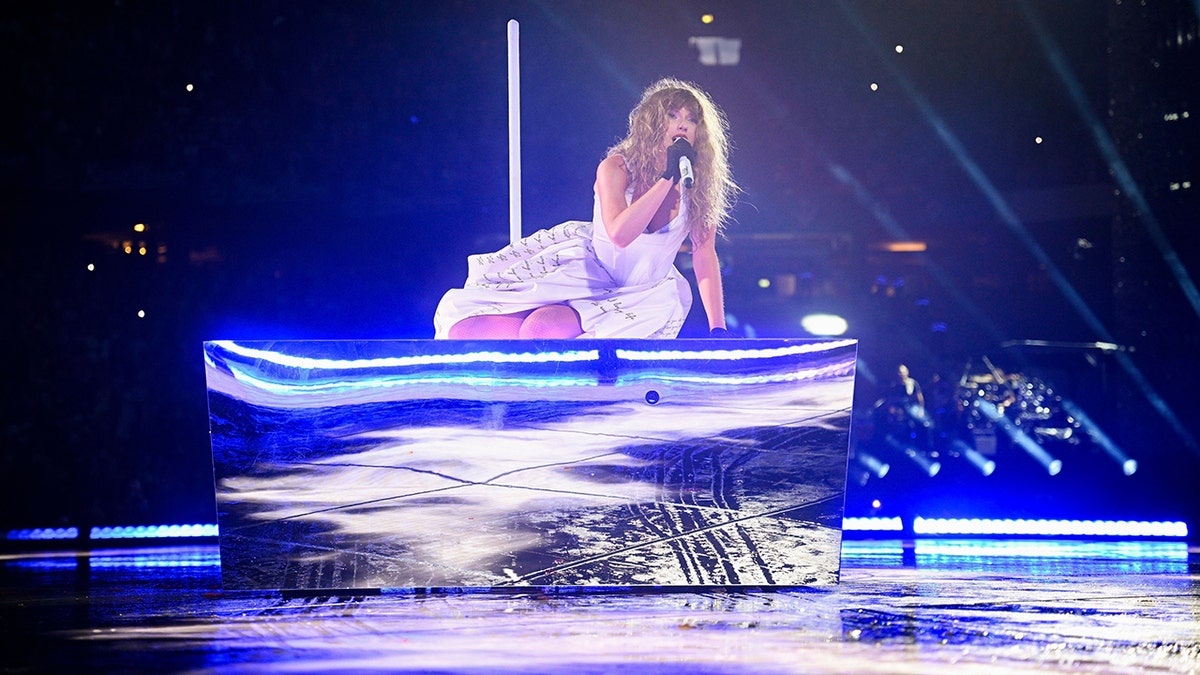 Taylor Swift sings and lies on a moving box that's a part of her stage