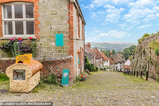 Button Cottage can be seen in the photograph nestling between two white properties