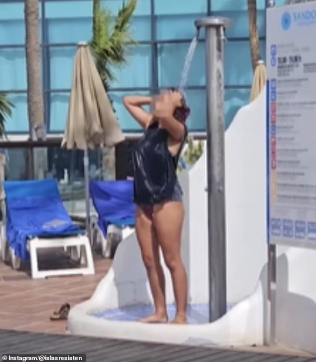 A woman is seen taking a shower by the hotel's pool as Lanzarote residents struggle with water cuts