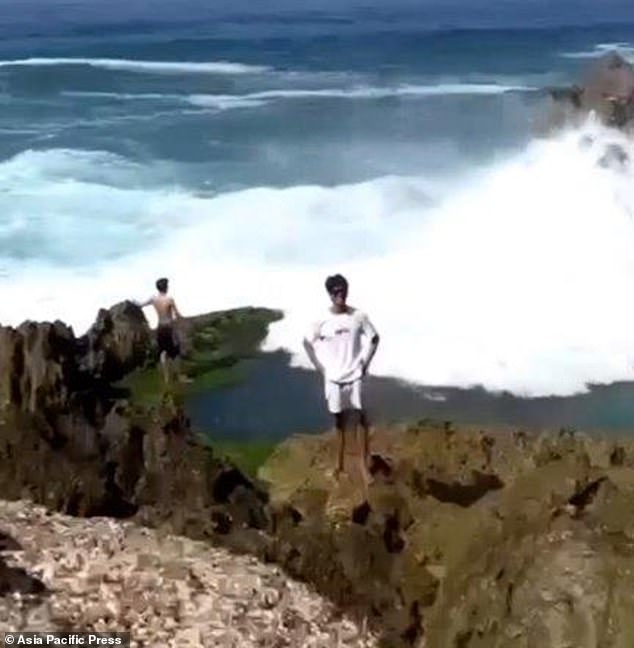 Simanjuntak could be seen standing behind his friend on the boulder before he was washed away