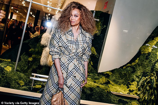 Tyra's long plaid trench coat was a rejection of Burberry's trend-chasing shorter coats from recent years. She wore it with long white mule heels and carried a gold sequined handbag