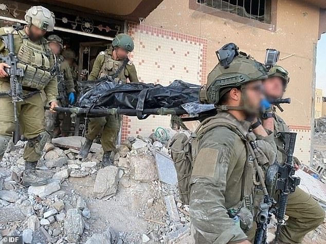 IDF soldiers carry Sinwar's body out of the wrecked building on a stretcher