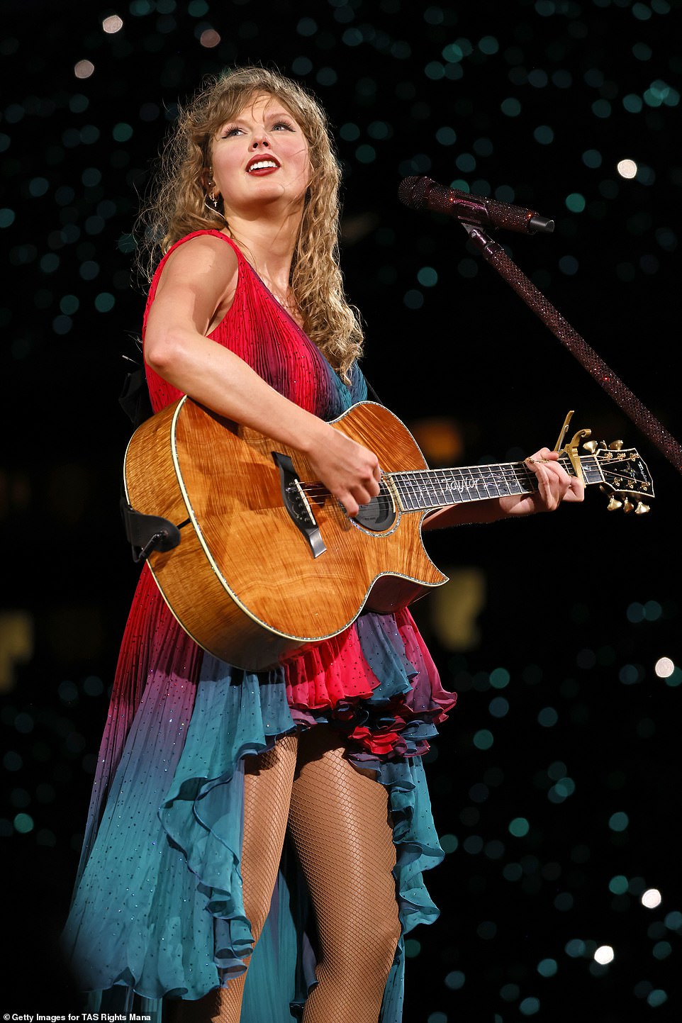 For her acoustic set, Swift turned heads wearing a sleeveless, teal and red-colored dress that fell down behind her