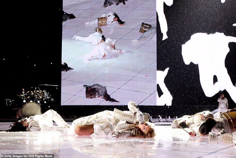 Swift could also be seen laying on the stage in a white, printed dress and jacket during The Tortured Poets Department set