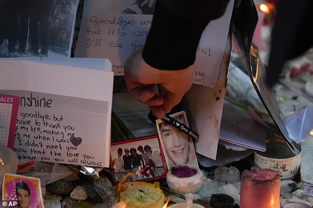 Liam Payne's father Geoff Payne takes a bracelet with the words 'I ¿¿ One Direction' while visiting a shrine outside the hotel where his son died