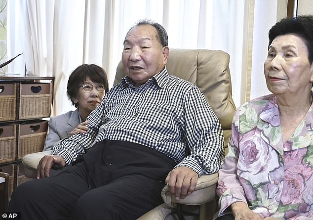 Iwao Hakamada, center, sits with his sister, right, as Tsuda came to his home to apologise