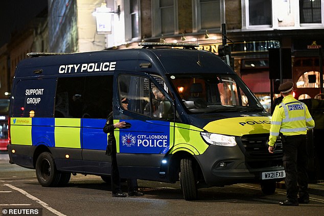 Police officers work as people gather outside the Old Bailey for the protest tonight