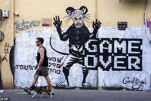 People pass by a newly painted graffiti depicting Hamas Leader Yahya Sinwar, days after he was killed by Israeli forces in Gaza, in Tel Aviv, Israel, on Sunday, Oct. 20, 2024