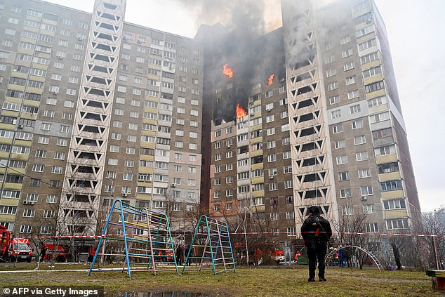 A law enforcement officer stands next to a residential building, damaged as a result of a missile attack in Kyiv on February 7, 2024