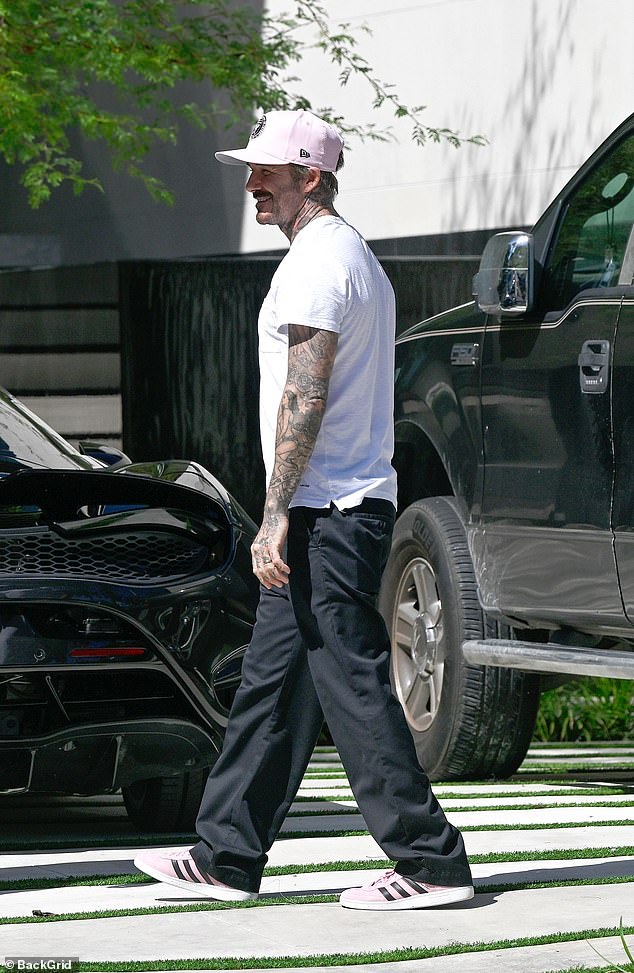 Beckham is photographed smiling for the cameras after driving into the gated property