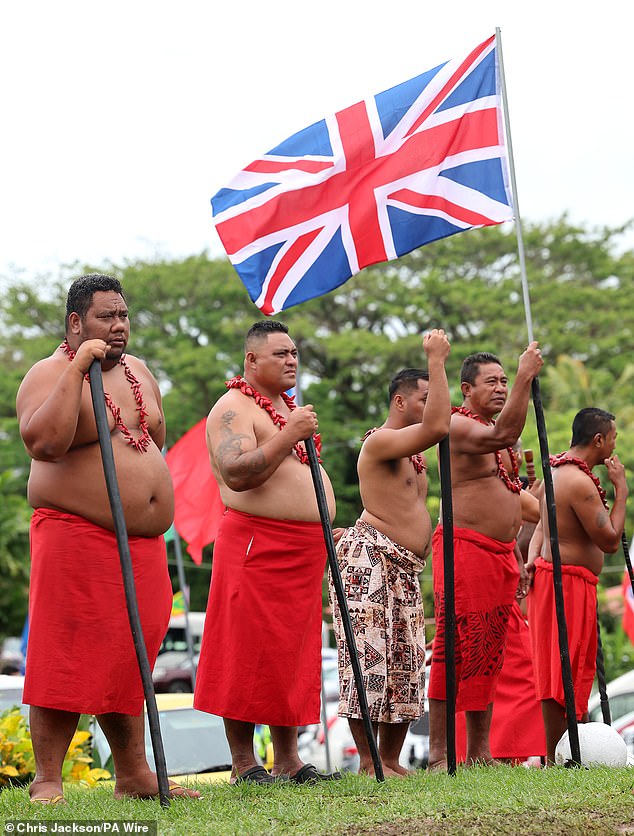 Village community members wait for the arrival of Britain's Charles and Camilla