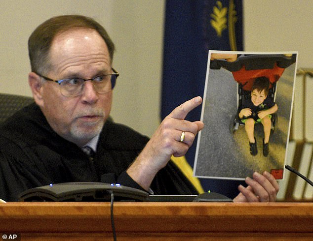 Superior Court Justice Charles Temple holds a photograph of Elijah Lewis as he explains his sentence at the hearing for Danielle Dauphinais at Hillsborough County Superior Court South in Nashua, New Hampshire on Friday