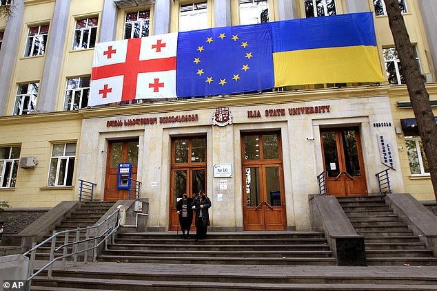 From left: Georgian national, EU and Ukrainian national flags hangs at a polling station during the parliamentary election in Tbilisi, Georgia, Saturday, Oct. 26, 2024