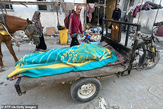 A body lies covered by a blanket on a cart outside the Kamal Adwan Hospital in Beit Lahia in the northern Gaza Strip on October 28, 2024