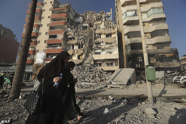 Lebanese women pass in front of a destroyed building hit in an Israeli airstrike in Tyre, Lebanon, Monday, Oct. 28, 2024