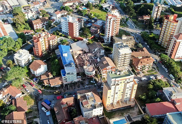 Dramatic aerial pictures show a pile of rubble where the building stood amongst other high rise blocks