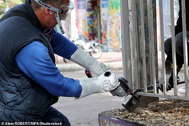 A worker in Marseille is seen cutting a lock box off a railing on October 28