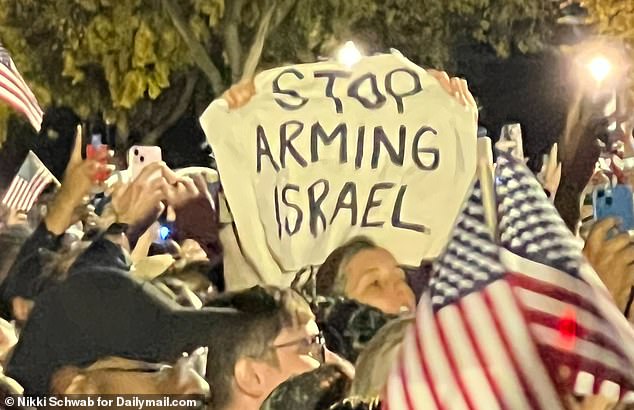 A demonstrator holds up a 'Stop Arming Israel' sign as Vice President Kamala Harris started her 'closing argument' speech at the Ellipse on the National Mall Tuesday night in Washington, D.C.