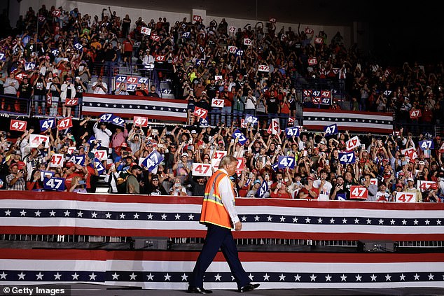 Trump walks into his event in Green Bay wearing an orange vest