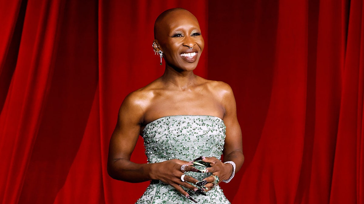 Cynthia Erivo smiling in a strapless light green gown