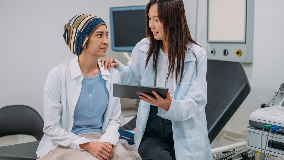 A female gynecologist talking to her patient about cervical cancer awareness and test results on an electronic tablet.