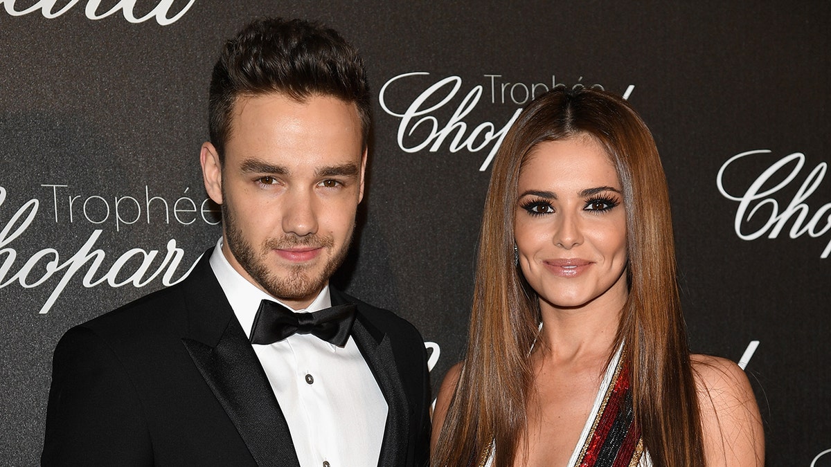 Liam Payne wears a tuxedo next to Cheryl Cole on red carpet.