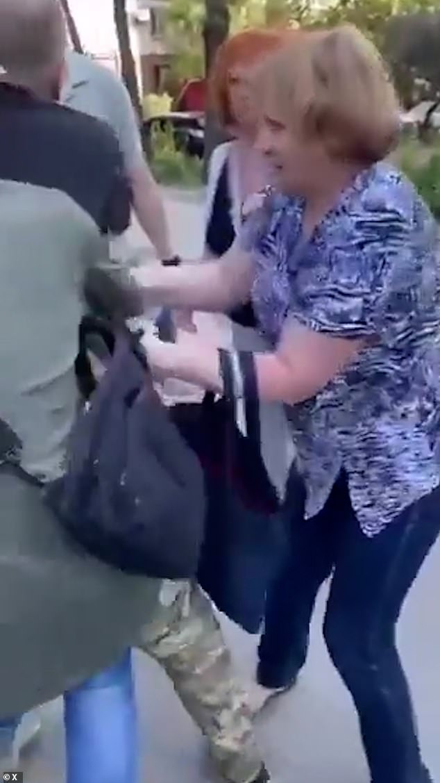 This woman grabs onto a man who is being dragged away by officers in yet another conscription video circulating on social media