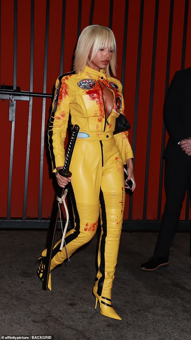 The model slipped into a blood-spattered yellow leather catsuit, with a machete in hand