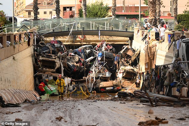 Members of the fire brigade, which are part of a search and rescue unit, carry out work as cars and debris block a tunnel after the recent flash flooding in the nearby municipality Benetusser on November 1