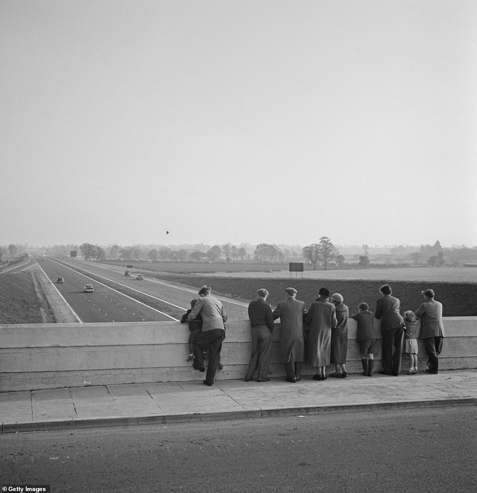 People marvel at the fast-moving traffic from a bridge over the newly-opened first section of the M1 motorway on 2 November 1959