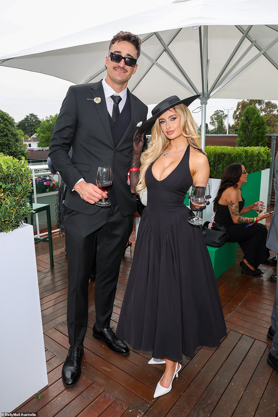 Australia's hottest WAG Chelsea Becirevic (right) put on a very busty display in a lowcut black gown as she arrived on the arm of her Port Adelaide star beau Ivan Soldo (left)