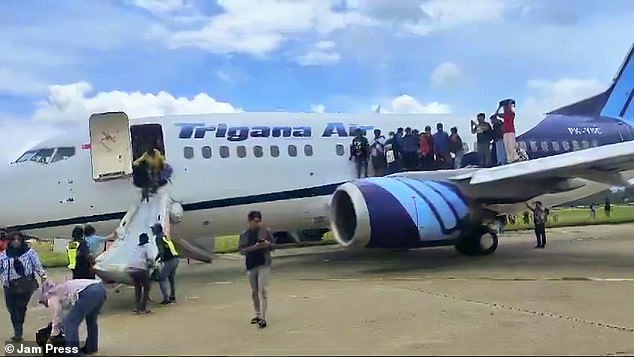 Picture shows people escaping from a plane through an emergency slide after a passenger spotted smoke coming out of the aircraft's engine